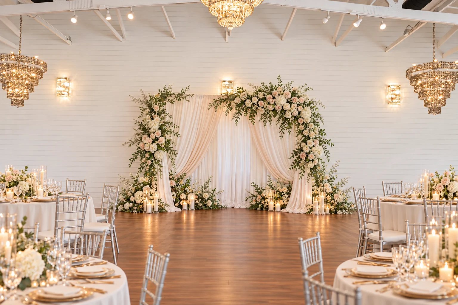 Wedding reception scene inside the ranch ballroom, with an ivory floral ceremony backdrop and candlelit guest tables
