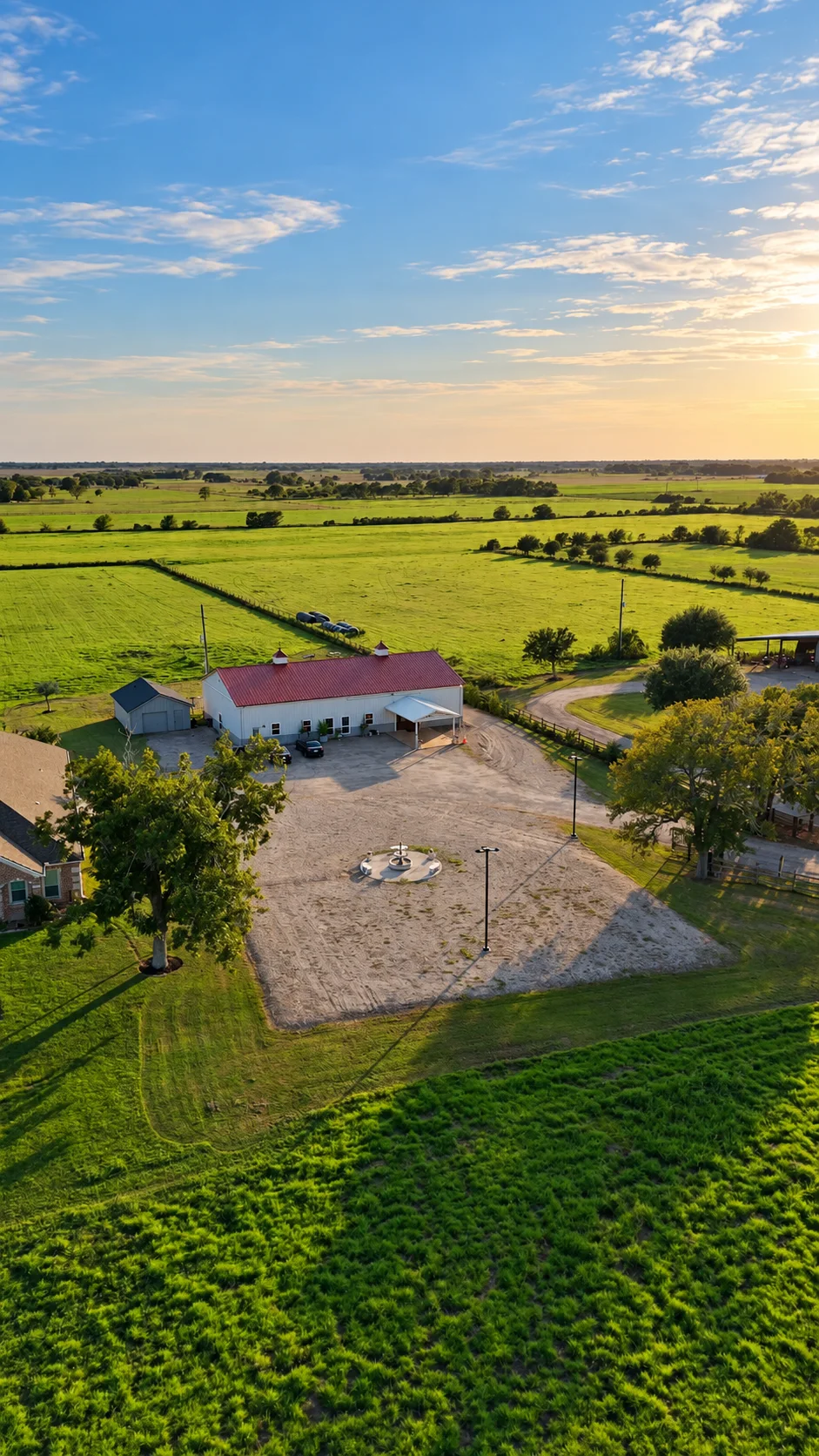 Aerial perspective of Texas AZ Paradise Ranch, its gravel forecourt, fountain, and neighboring green fields in Richmond, Texas.