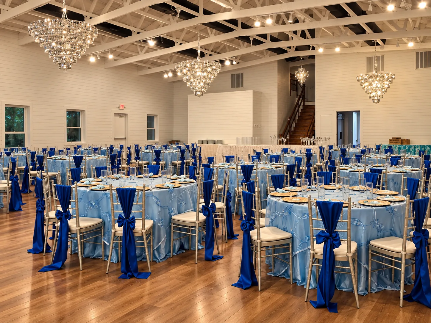 Side view of blue reception tables, chandeliers and white trusses in the Richmond ranch hall.