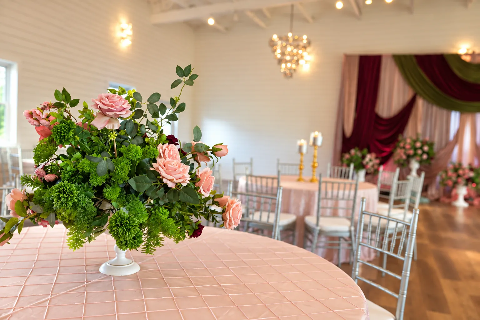 Blush rose centerpiece on a reception table with the ranch hall visible behind it in Richmond, Texas.